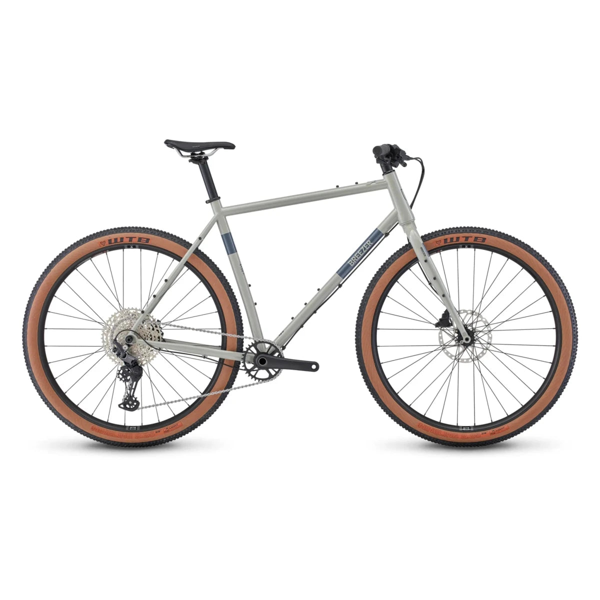 Breezer Radar Sport adventure gravel bike – A light grey steel adventure bicycle with flat handlebars, knobby tan-wall WTB tires, and a 1x drivetrain, shown from the side against a white background.