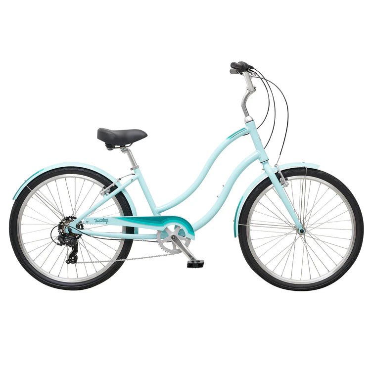 Light blue step-through cruiser bicycle – A light blue women's cruiser bicycle with a low-step frame, matching fenders, teal chain guard accents, upright handlebars, and wide black tires, shown in side profile against a white background.
