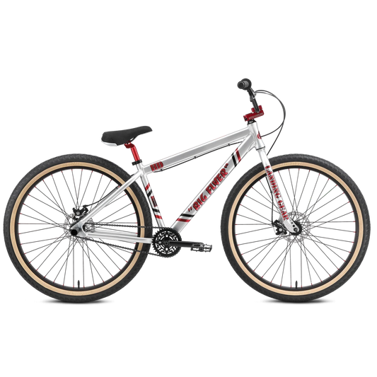 SE Big Flyer HD 29 inch cruiser bike – Profile view of a silver SE 29-inch BMX cruiser bike with red accents, disc brakes, and tan-wall tires against a clean white background.