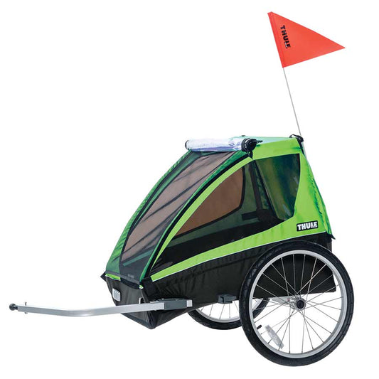 Thule Cadence 2 green bike trailer – Bright green and black bicycle trailer with mesh front cover, large spoked wheels, silver tow arm, and a tall red safety flag on a white background.