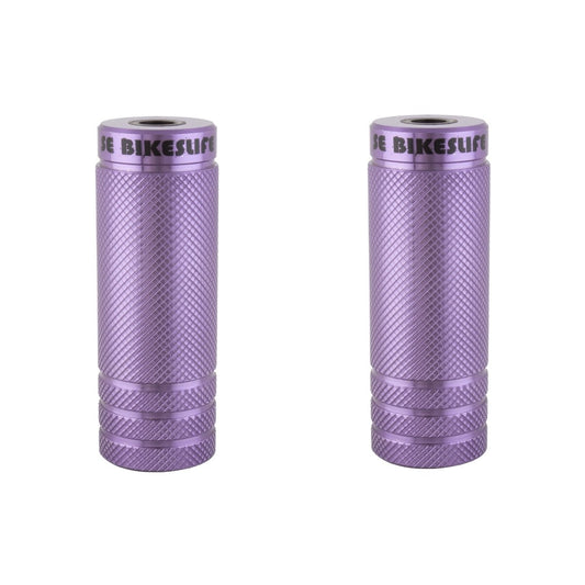 Purple SE Bikes Life knurled wheelie pegs – A pair of metallic purple cylindrical bicycle pegs stand upright side by side against a white background, featuring knurled diamond grip patterns and engraved SE Bikes Life branding.
