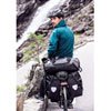 Black Ortlieb Back Roller panniers on bike – A cyclist rides on a mountain road with a pair of black waterproof Ortlieb Back Roller panniers and a rack bag mounted to the rear bicycle rack.