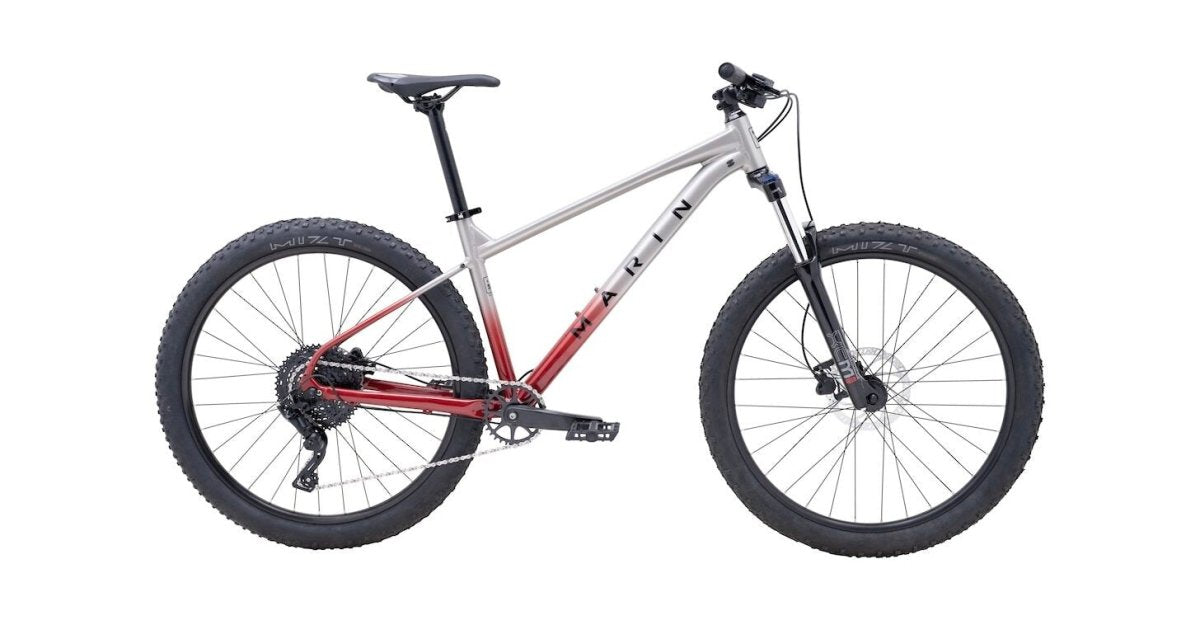 Silver and red Marin Bobcat Trail 3 29er – Profile view of a hardtail mountain bike featuring an aluminum frame that fades from silver to metallic red, black knobby 29er tires, and front suspension against a white backdrop. – Marin Bobcat Trail 3 29er Hardtail Mountain Bike