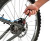 Park Tool Y hex wrench adjusting disc brake – A person's hand grips a three-way Y hex wrench to adjust the rear disc brake caliper on a silver mountain bike wheel.