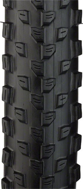 Black CST Patrol mountain bike tire tread – Close-up of a black mountain bike tire showing a textured knobby rubber tread pattern with grooved center blocks and pronounced shoulder lugs on a white background.