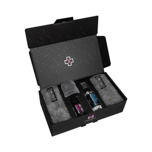 Muc-Off ceramic protection coating kit – Open black gift box presenting Muc-Off ceramic coating bottles, an applicator sponge, and two grey microfiber cloths fitted neatly inside custom cardboard inserts against a white backdrop.