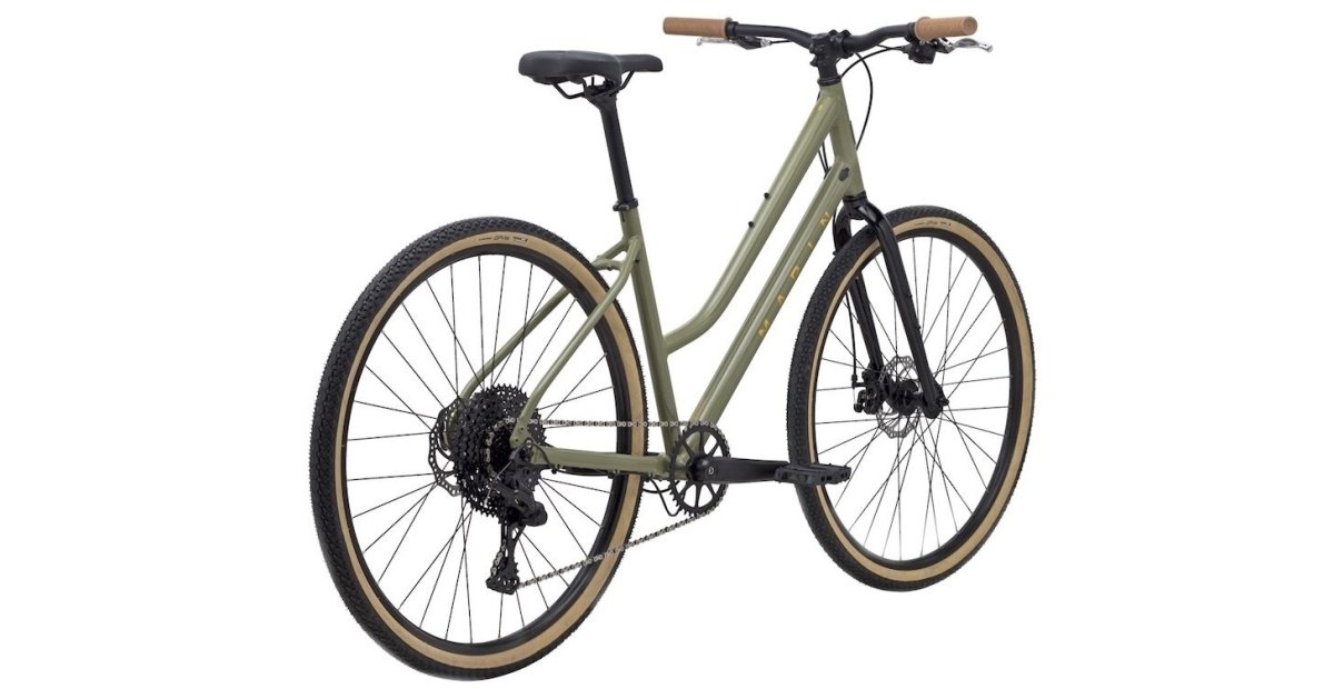 Sage green Marin hybrid step-through bicycle – This step-through hybrid bicycle features a sage green aluminum frame, tan sidewall tires, a wide-range rear cassette, flat handlebars, and disc brakes against a plain white background.