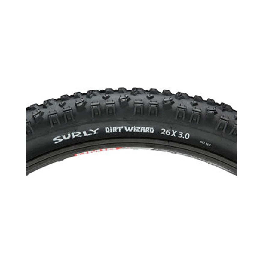 Surly Dirt Wizard 26x3.0 mountain bike tire – Close-up profile of a black knobby mountain bike tire mounted on a rim against a white background, featuring aggressive tread lugs and white Surly Dirt Wizard 26x3.0 lettering along the sidewall.