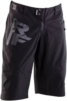 RaceFace Agent men's winter shorts in black – Black mountain bike shorts featuring a prominent RF logo on the right thigh, zippered waterproof pockets, snap closure, and articulated knees, displayed on a solid white background.