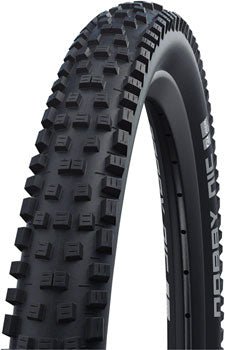 Schwalbe Nobby Nic mountain bike tire – A close-up three-quarter view of a black knobby mountain bike tire mounted on a rim against a plain white background, showing aggressive blocky tread.