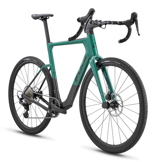 Fuji Jari Carbon gravel adventure bike – This green and matte black gravel bike features flared drop handlebars, disc brakes, and knobby Maxxis all-terrain tires, shown against a plain white background.