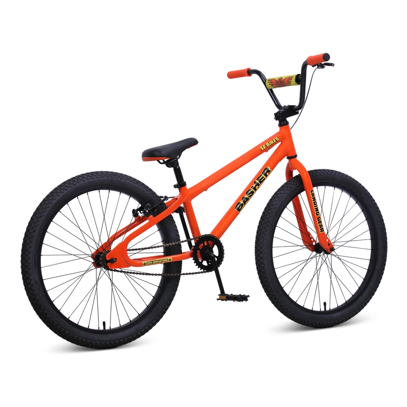 Orange SE Basher 24 inch BMX cruiser – A bright orange BMX cruiser bike is shown in a three-quarter rear studio view against a white background, featuring black tires, black high-rise handlebars, and orange grips.
