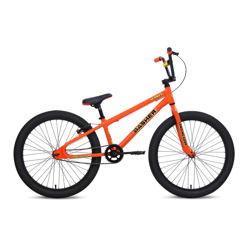 SE Basher 24-inch orange BMX cruiser – Bright orange BMX cruiser bicycle with black tires, black handlebars, Landing Gear forks, and Basher decals, shown in profile against a plain white studio background.