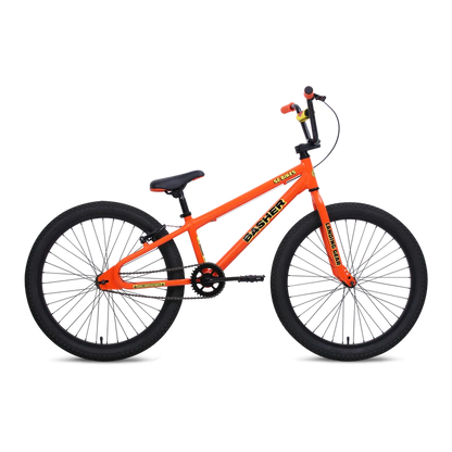 SE Basher 24-inch orange BMX cruiser – Bright orange BMX cruiser bicycle with black tires, black handlebars, Landing Gear forks, and Basher decals, shown in profile against a plain white studio background.