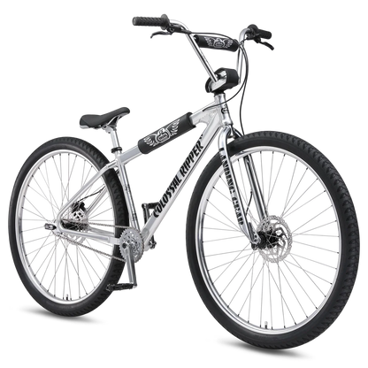 Silver SE Colossal Ripper 32 BMX cruiser – A polished silver BMX cruiser bike stands angled against a white background, featuring large 32-inch wheels, black protective frame pads, disc brakes, and wide handlebars.