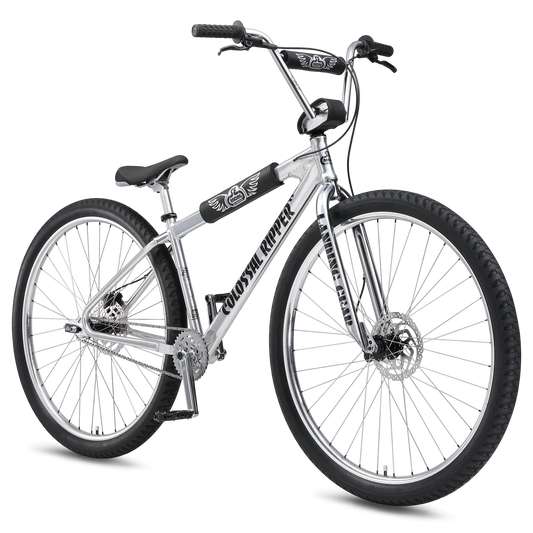Silver SE Colossal Ripper 32 BMX cruiser – A polished silver BMX cruiser bike stands angled against a white background, featuring large 32-inch wheels, black protective frame pads, disc brakes, and wide handlebars.