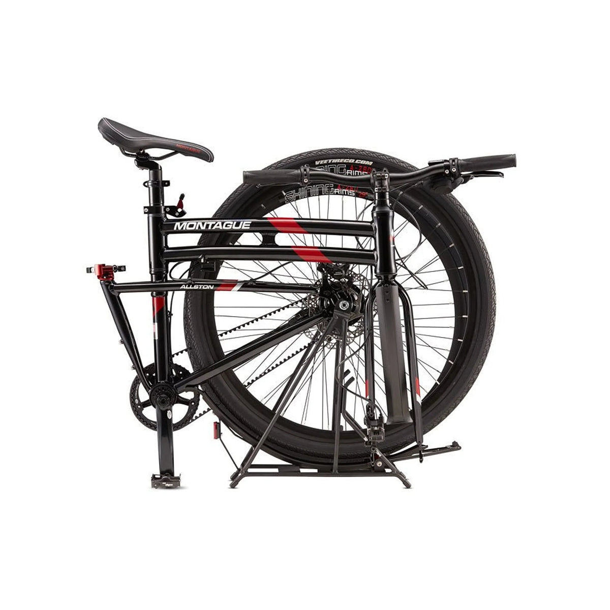 Montague Allston folding bike folded position – A matte black Montague Allston folding bike stands collapsed against a white background, showing its folded frame with red graphics, belt-drive system, and rear wheel.
