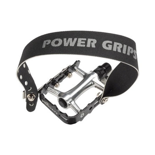 Power Grips pedal with black strap – A silver aluminum bicycle pedal with black side cages features a wide, arched black diagonal foot strap with the Power Grips logo on a white background.