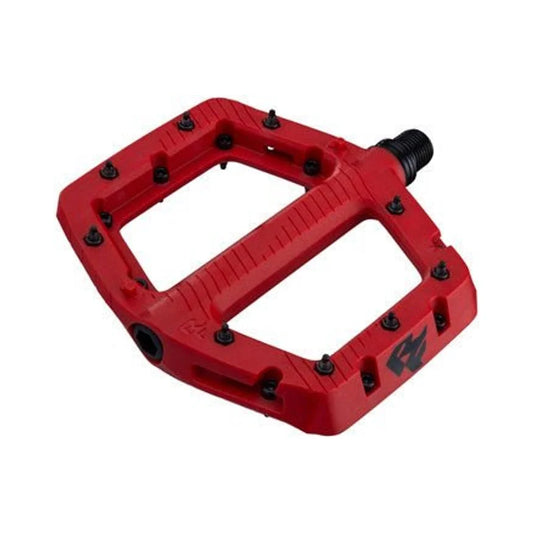 Red RaceFace Chester composite platform pedal – A vibrant red composite platform bicycle pedal features black traction pins around the perimeter, a ridged center beam, and a black threaded spindle against a plain white background.